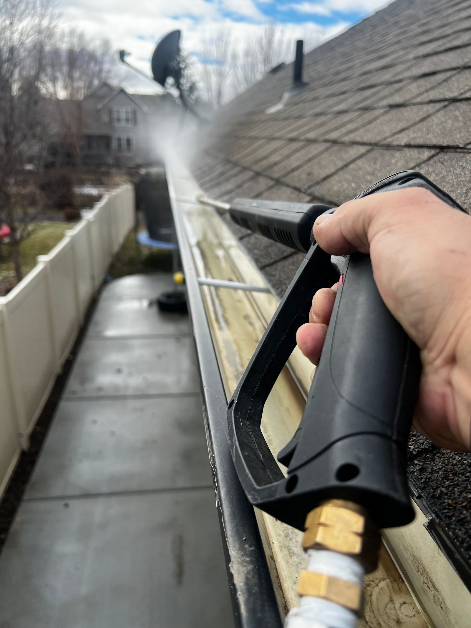 Technician cleaning debris from a residential roof gutter